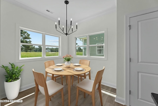 dining room with baseboards, visible vents, ornamental molding, wood finished floors, and a chandelier