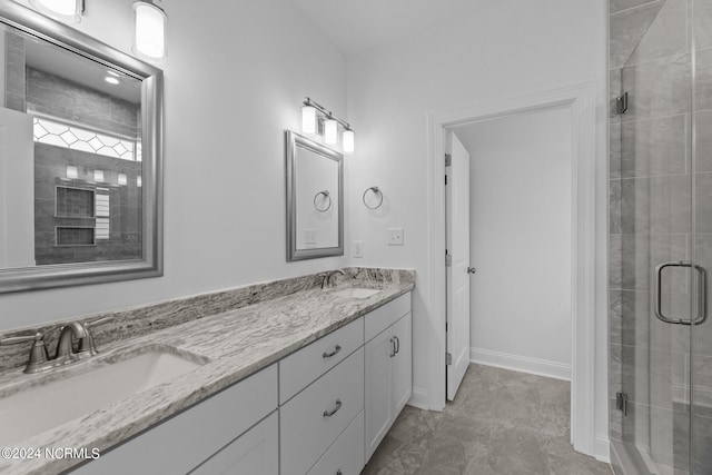 full bath with a sink, a shower stall, and double vanity