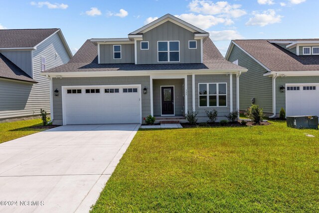 view of front of house with a garage, concrete driveway, roof with shingles, board and batten siding, and a front yard