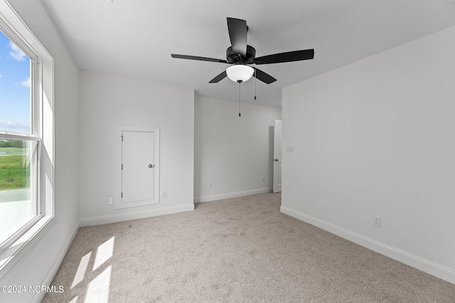 empty room with ceiling fan, baseboards, and light colored carpet