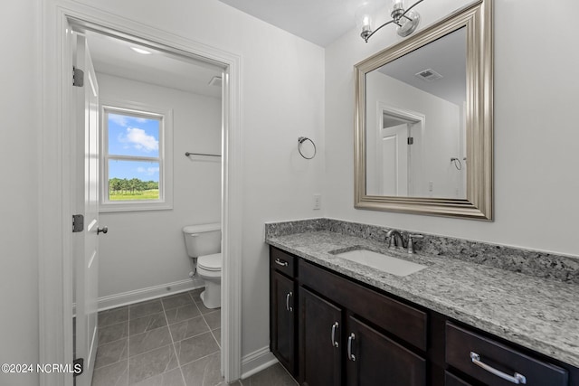 bathroom featuring toilet, vanity, visible vents, baseboards, and tile patterned floors