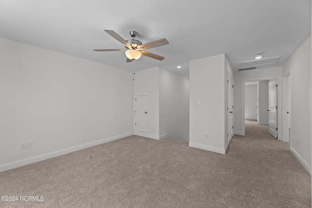 spare room with light colored carpet, visible vents, attic access, ceiling fan, and baseboards