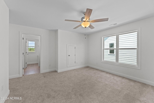 carpeted empty room featuring ceiling fan, visible vents, and baseboards