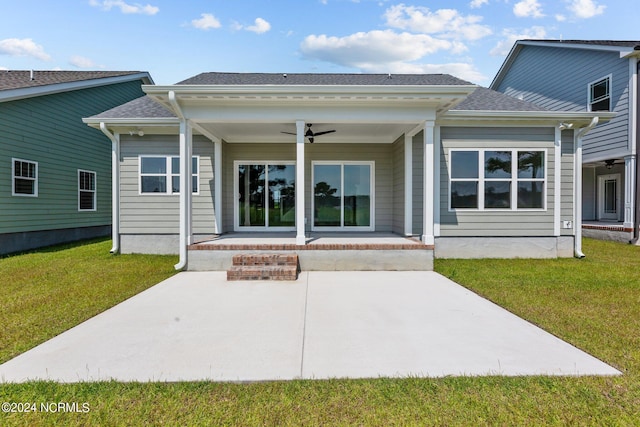 back of house with ceiling fan, roof with shingles, a lawn, and a patio area