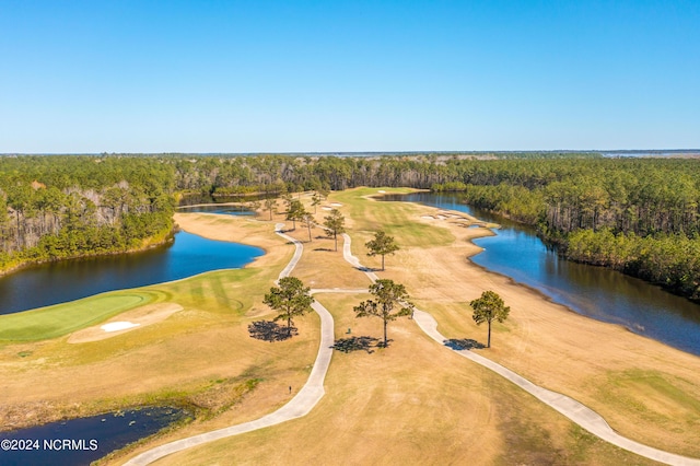 birds eye view of property with golf course view, a water view, and a view of trees