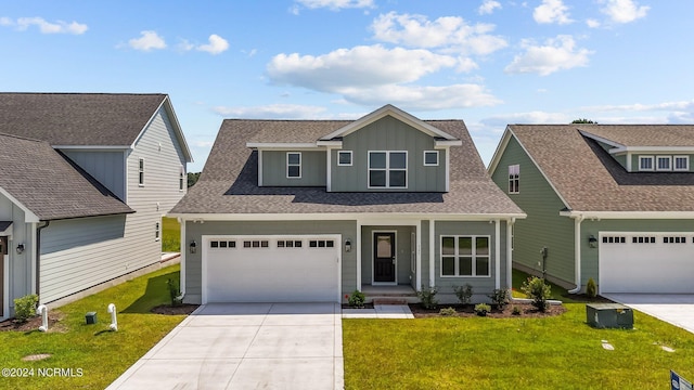 traditional-style house featuring a shingled roof, concrete driveway, board and batten siding, a front yard, and a garage