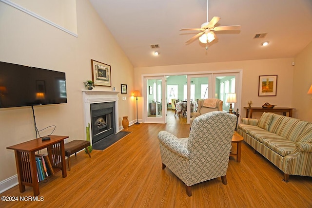 living room with ceiling fan, light hardwood / wood-style floors, and vaulted ceiling