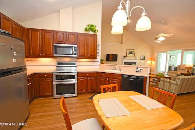 kitchen with ceiling fan with notable chandelier, appliances with stainless steel finishes, decorative light fixtures, light hardwood / wood-style floors, and kitchen peninsula