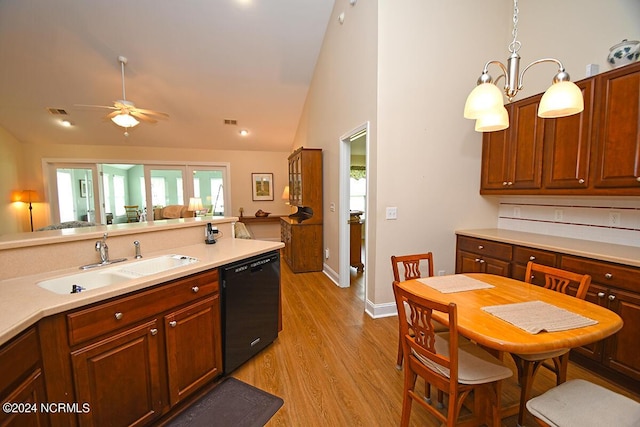 kitchen featuring light wood-type flooring, vaulted ceiling, sink, pendant lighting, and black dishwasher