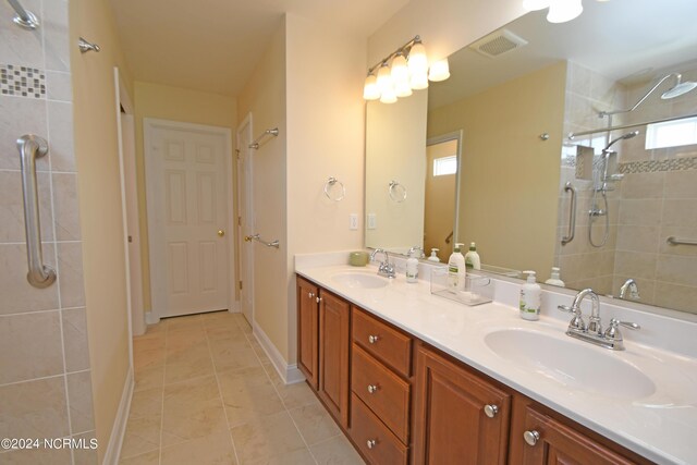 bathroom featuring tile patterned floors, vanity, and a tile shower