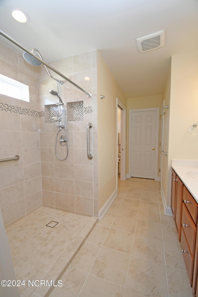 bathroom with a tile shower and vanity