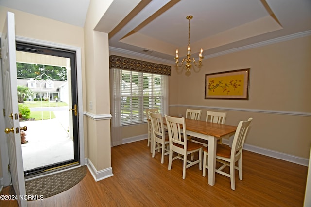 dining room with a chandelier, hardwood / wood-style floors, and a raised ceiling