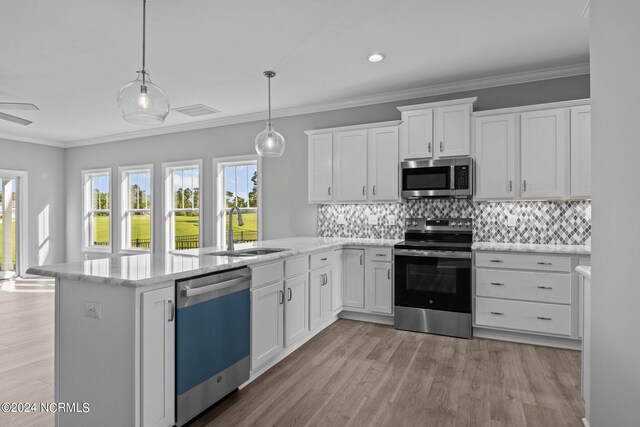 kitchen with sink, hanging light fixtures, appliances with stainless steel finishes, white cabinets, and light wood-type flooring