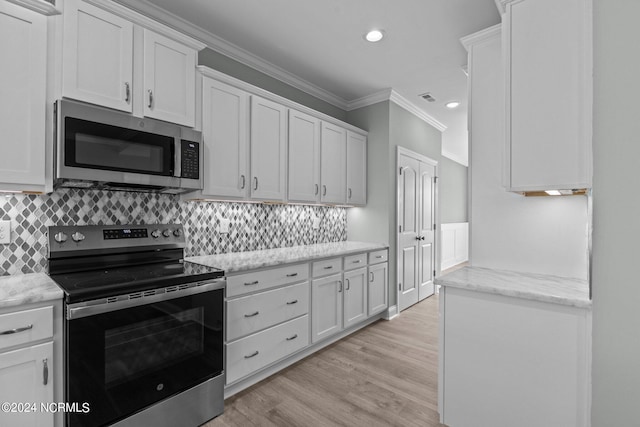 kitchen featuring white cabinets, light hardwood / wood-style floors, ornamental molding, and appliances with stainless steel finishes