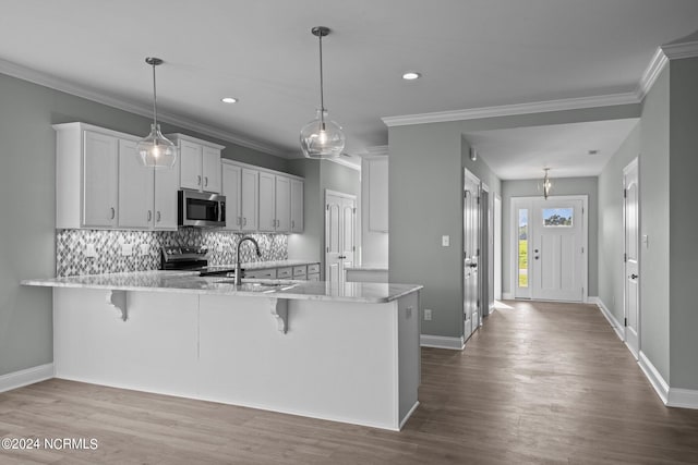 kitchen featuring kitchen peninsula, a breakfast bar, white cabinets, and pendant lighting