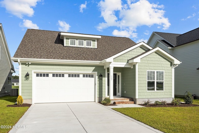 craftsman-style house featuring central AC unit, a garage, and a front lawn