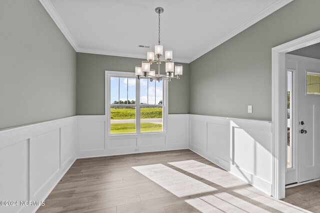 unfurnished dining area with crown molding, light hardwood / wood-style flooring, and an inviting chandelier