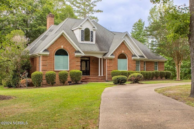 view of front of house with brick siding, a shingled roof, a chimney, crawl space, and a front yard