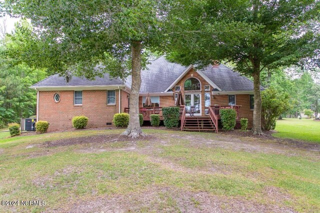 view of front of home with brick siding, a shingled roof, a front yard, crawl space, and a deck