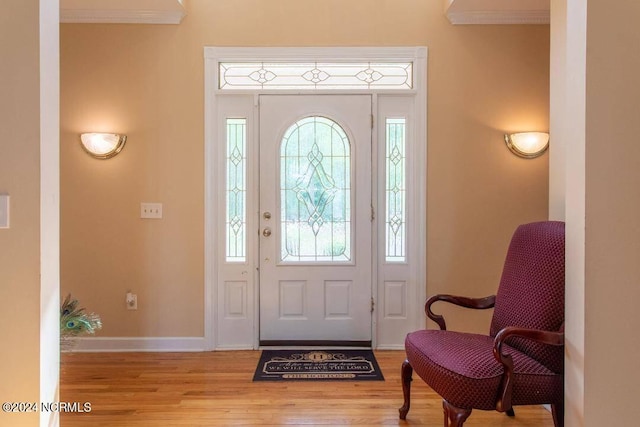 entryway featuring baseboards, crown molding, plenty of natural light, and light wood-style floors