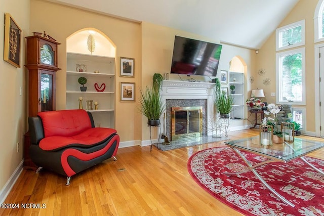 living room with hardwood / wood-style floors, built in features, and a high end fireplace