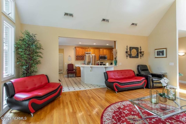 living room with lofted ceiling, a wealth of natural light, and light hardwood / wood-style flooring