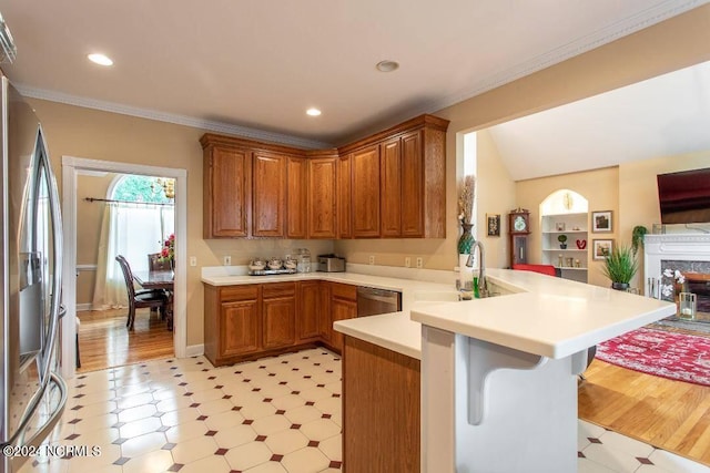 kitchen with a peninsula, appliances with stainless steel finishes, light countertops, and ornamental molding