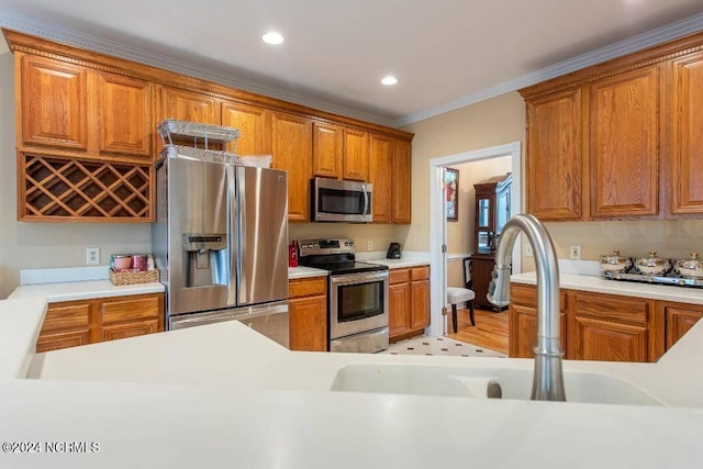 kitchen with appliances with stainless steel finishes, brown cabinetry, a sink, and light countertops