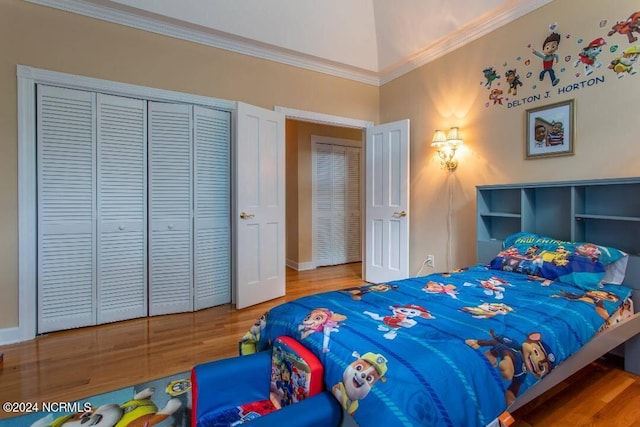 bedroom with crown molding, a closet, wood-type flooring, and vaulted ceiling