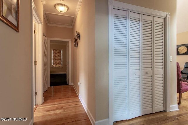 hall featuring light wood finished floors, baseboards, and crown molding