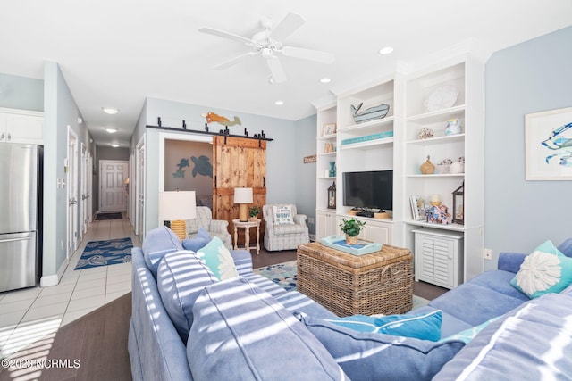 tiled living room with a barn door and ceiling fan