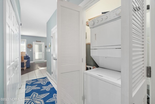 laundry area with light tile patterned floors and stacked washing maching and dryer