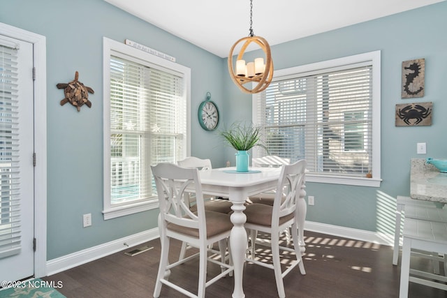 dining area featuring dark hardwood / wood-style flooring, a wealth of natural light, and an inviting chandelier