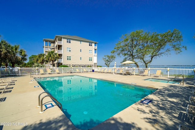 view of pool featuring a water view and a patio area