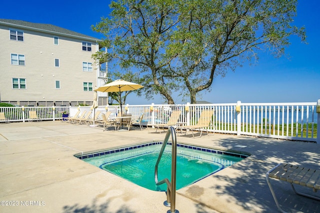 view of pool featuring a water view and a patio area