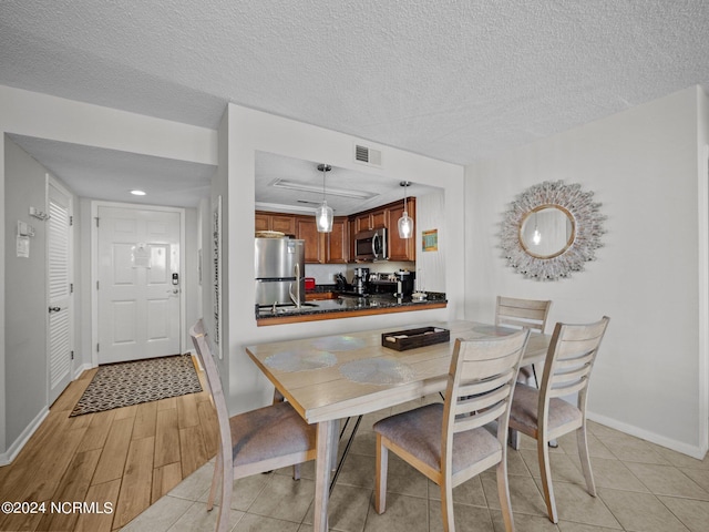 dining room with light wood-type flooring and a textured ceiling