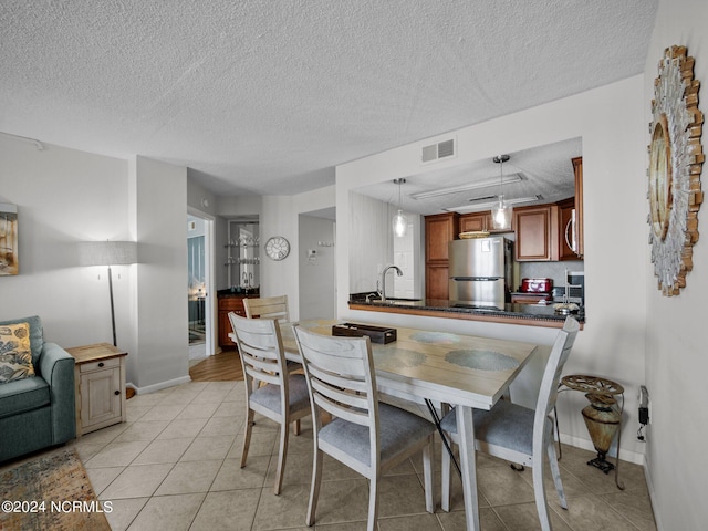 dining space featuring sink, light tile patterned floors, and a textured ceiling