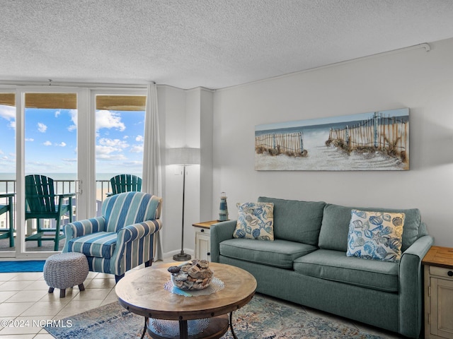 living room with light tile patterned floors, a textured ceiling, a water view, and expansive windows