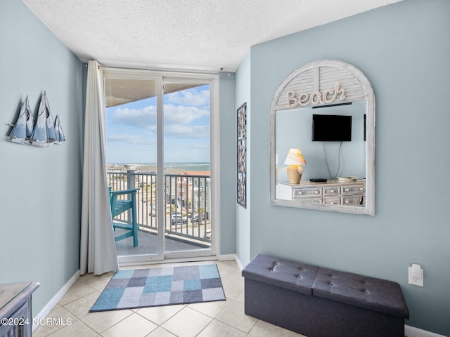 doorway to outside with light tile patterned floors, a textured ceiling, and a wall of windows