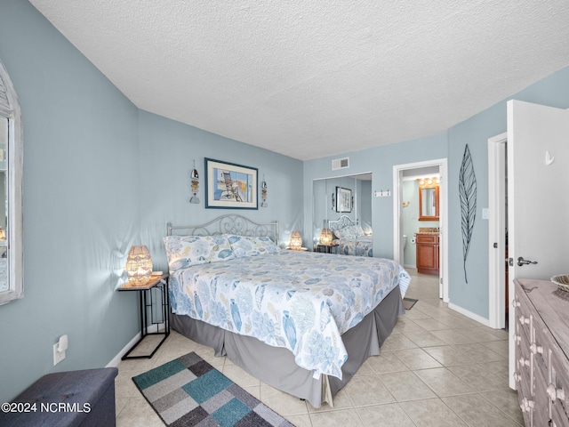 tiled bedroom featuring a textured ceiling and ensuite bath