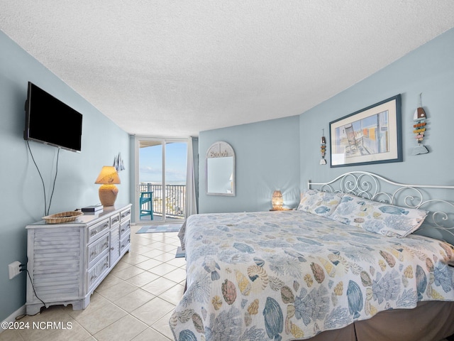 bedroom with light tile patterned flooring, a wall of windows, a textured ceiling, and access to outside