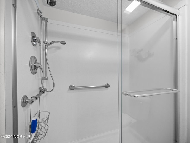 bathroom featuring a shower with door and a textured ceiling