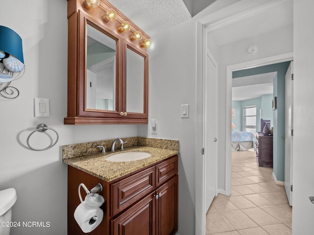 bathroom featuring tile patterned floors, vanity, a textured ceiling, and toilet