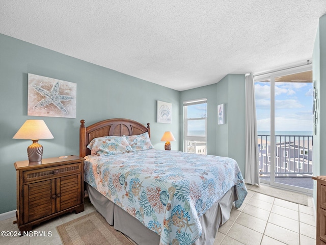 tiled bedroom featuring a textured ceiling, access to outside, and a water view