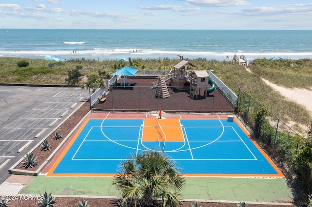 view of basketball court with a water view, a playground, and a view of the beach