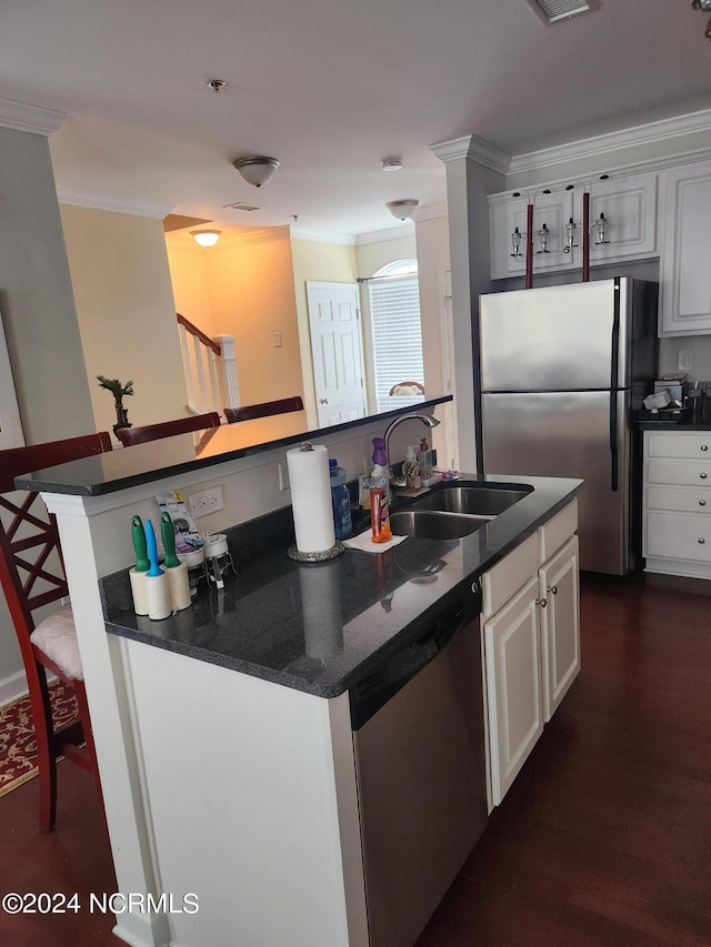 kitchen with crown molding, a center island with sink, stainless steel appliances, and a sink