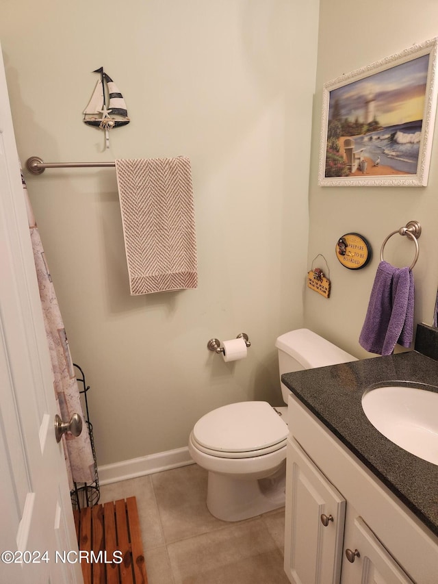 bathroom with toilet, vanity, baseboards, and tile patterned floors