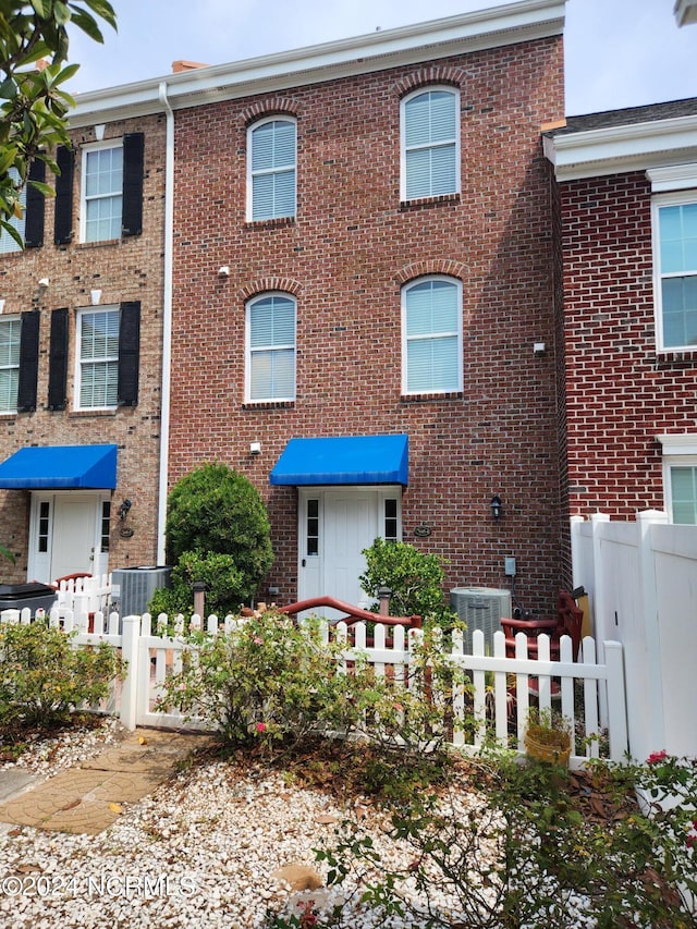 view of front of house with fence, cooling unit, and brick siding