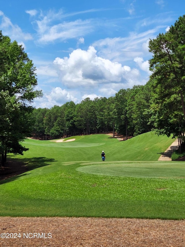 surrounding community with a forest view, a lawn, and golf course view