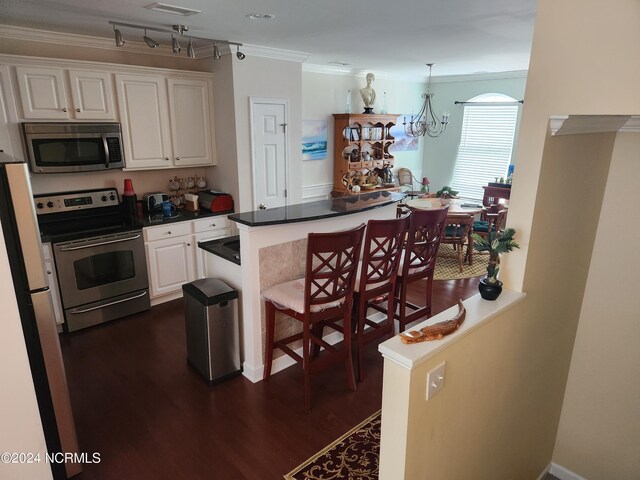 kitchen featuring white cabinets, dark wood-style floors, a breakfast bar area, ornamental molding, and stainless steel appliances